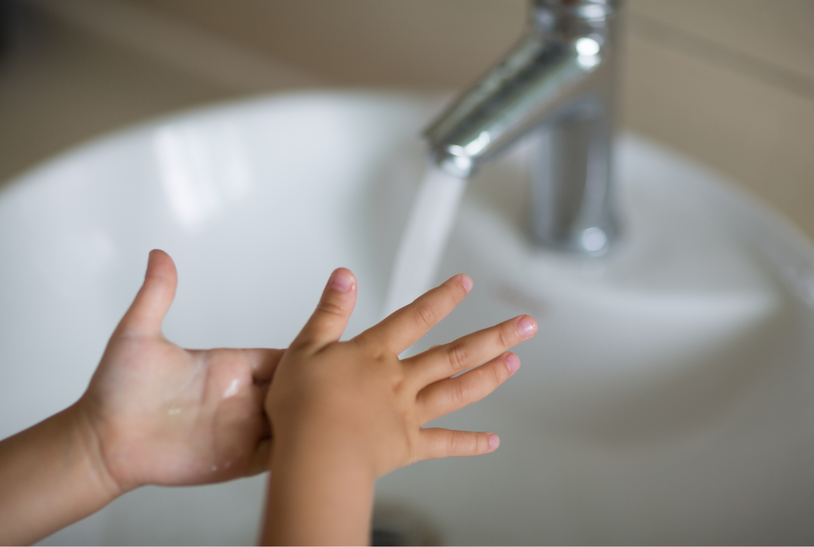 Kid washing their hands at the faucets for schools