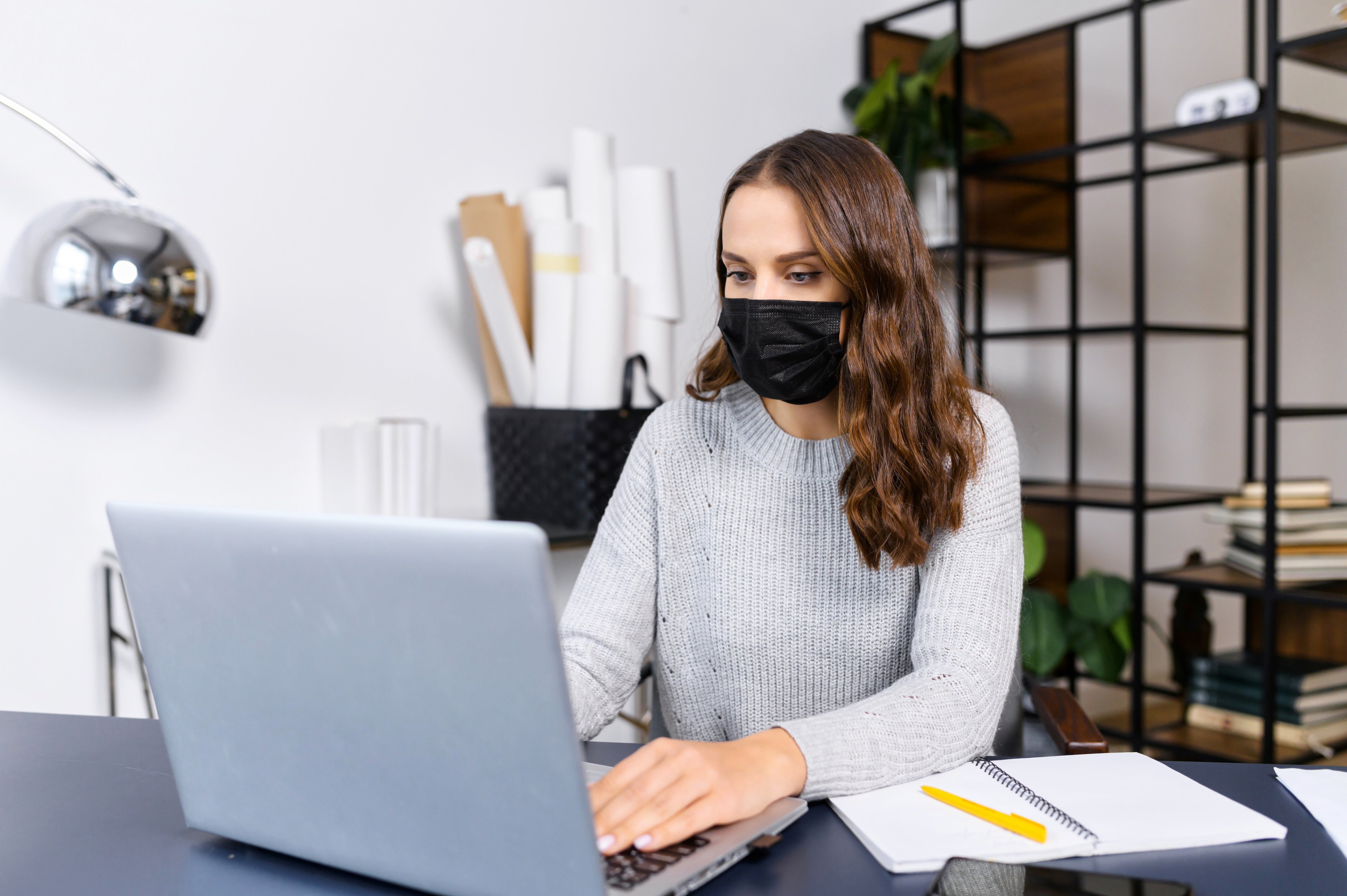 Woman working in her office wearing a mask to promote post-pandemic workplace safety